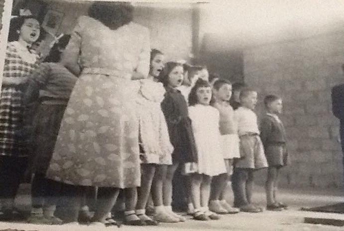 Miss Arshaluys Derderian standing backwards teaching songs to the students of the Aghpalian primary school of Chtaura Lebanon